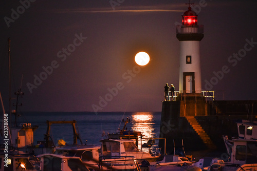 Foto  Un couple une lune et un phare