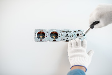 Wall Mural - Close-up of an electrician mounting electric sockets on the white wall