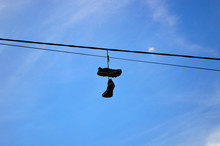 Sneakers Hanging On The Wire Against The Blue Sky