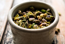 Close Up Of Pistachios In Bowl On Wooden Table