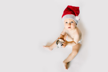 Adorable smiling child wearing red Christmas cap holding christmas ball isolated on white