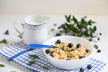 Healthy breakfast. Oatmeal with blueberries, a teaspoon with cereal and berry, milk jug with milk