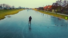 Drone Shot Of A Boy Ice Skating In A Typical Dutch Landscape With Windmills In The Background