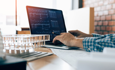 engineering man using laptop and sitting in modern office working blueprint project.