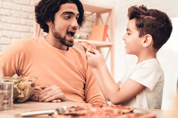 Wall Mural - Happy Arabian Family Eating Pizza in Kitchen.