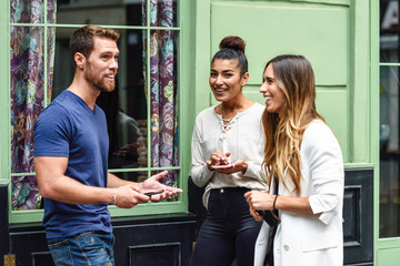 Wall Mural - Three multiethnic people friends talking and smiling outdoors