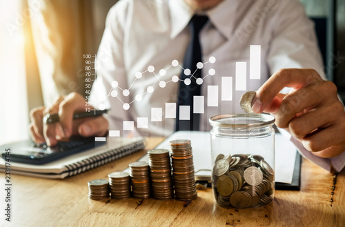 Cuadros en Lienzo businessman holding coins putting in glass with using smartphone and calculator