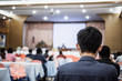 © smolaw11 - Speaker on stage, rear view audience listens for speech lecturer in conference hall or seminar meeting, business and education concept