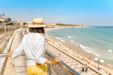 Wall Mural - Young woman in hat looking at the beach in Tarragona, Costa Dorada