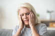 © fizkes - Upset middle aged older woman massaging temples touching aching head feeling strong headache or migraine concept, sad tired stressed elderly senior mature woman suffering from pain or dizziness