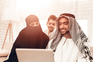 Poster - Young Arabic Family Using Laptop on Sofa at Home.