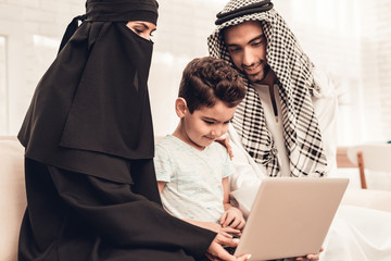 Poster - Young Arabic Family Using Laptop on Sofa at Home.