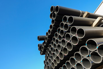 Plastic pipes in the assortment of finished products packed in packages against a blue sky