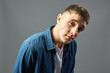 © Leika production - Portrait  guy dressed in white t-shirt and a jeans shirt on the gray background  in the studio