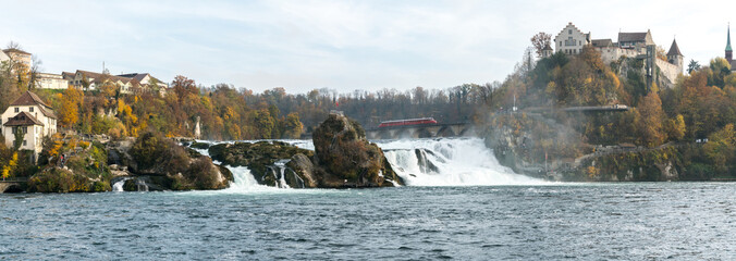 Poster - a red arrow train stops on top of the bridge at Rhine Falls to view the wonderful waterfall landscape and the castle at Laufen in Switzerland