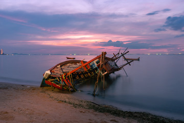 Wall Mural - Old fishing boat shipwrecks disposed on the beaches of the eastern coast of Thailand, view and landscape of the sea on sunset and sand with cloud sky.