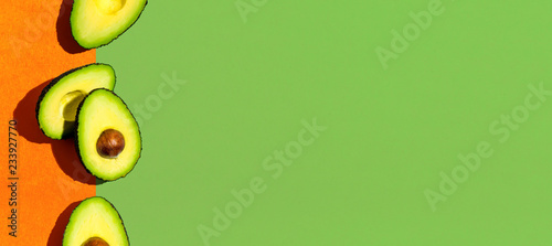 Fotografía Fresh avocado pattern on a green and orange background flat lay