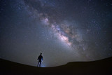 Fototapeta  - Milky way galaxy with a man standing and watching at Tar desert, Jaisalmer, India. Astro photography.