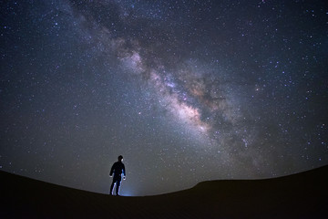 milky way galaxy with a man standing and watching at tar desert, jaisalmer, india. astro photography