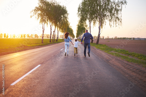 Fotografia, Obraz Happy family dad mom and son, playing, run away in the fresh air on the road nea