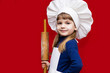 © Svetlana - Happy little girl in chef uniform holds rolling pin isolated on red. Kid chef. Cooking Process Concept