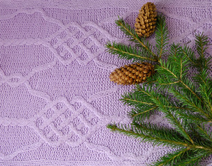 Wall Mural - Christmas and New Year. Spruce branches with cones are on the homemade knitted beautiful pattern background. Needlework.