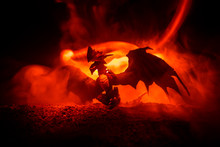 Silhouette Of Fire Breathing Dragon With Big Wings On A Dark Orange Background