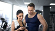 © motortion - Woman with trainer checking amount of burned calories in smartphone application