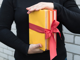 The girl is holding three books tied with a red ribbon. Present. Symbol of Training. Parents.