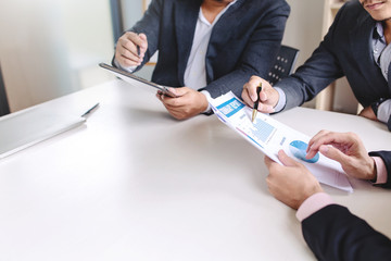 Business people pointing graph in meeting to analyze and discuss the situation on the financial report paper.