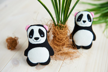 two soft toys panda next to an artificial palm tree