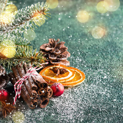 Wall Mural - Cinnamon sticks, fir branches and dry oranges on a dark green background with bokeh lights. Christmas greeting card