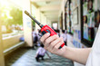 © titikul_b - A man holding a red radio communication or handheld walkie-talkie at school.