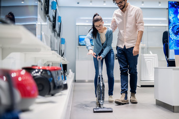 Canvas Print - Woman trying out vacuum cleaner in tech store. New technologies concept.