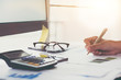 © Natee Meepian - Close up view of bookkeeper or financial inspector hands making report, calculating or checking balance. Home finances, investment, economy, saving money or insurance concept