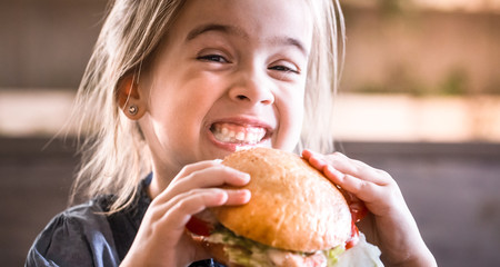 a little girl eats a sandwich in a cafe