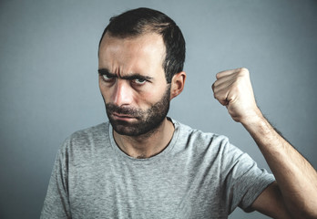 Wall Mural - Caucasian angry man on gray background.