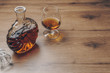a snifter glass of brandy and a brandy decanter on the wooden table