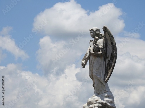 Fotografía Ancient statue of an angel holding a cross in his hands