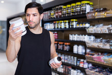 Young Muscular Sportman Looking Sport Dietary Supplements In Store