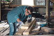 © Руслан Галиуллин - Man in a plaid shirt and jeans planing wood manual planer in the workshop