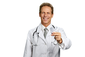 Portrait of happy medical doctor with pills. Smiling male doctor holding two packs of pills and looking at camera, isolated on white background.