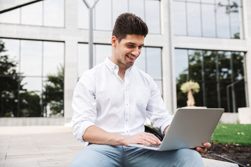 Wall Mural - Smiling young business man working on laptop computer