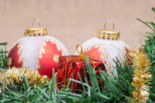 Fotografie, Obraz Winter holiday decoration: tinsel garland with Christmas gift decor and colorful tree balls on burlap background