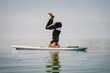Young flexible man on paddle board practicing yoga