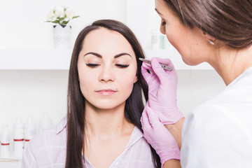 Sticker - Beautician plucks a young woman's eyebrows with tweezers