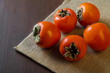 Wall Mural - Persimmon on a burlap on a wooden table.