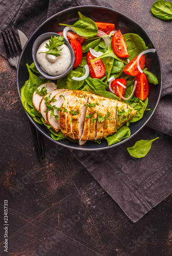 Fotografie, Obraz Grilled chicken breast salad with spinach, tomatoes and Caesar dressing, dark background
