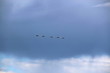 five jet fighters in the sky against a rain cloud background