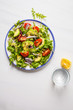 Healthy arugula, avocado, tomatoes salad on white marble background.